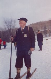 Photograph of Sigurd Lockeberg with his skis, and holding poles in one hand.